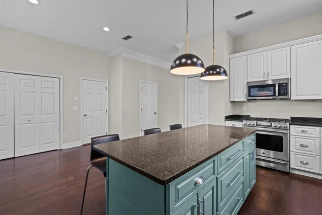 a kitchen with kitchen island granite countertop a stove a sink a refrigerator and a granite counter tops