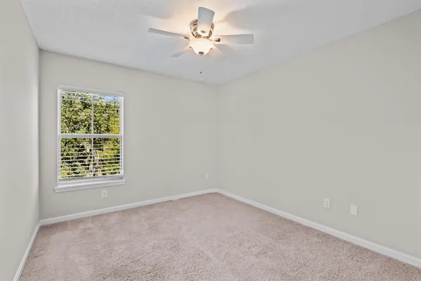 an empty room with windows and ceiling fan view