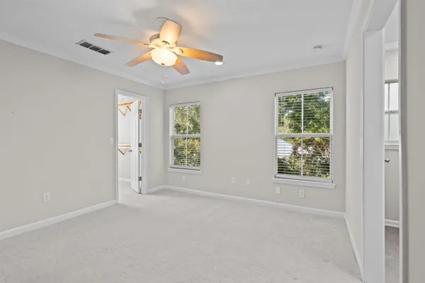 en empty room with windows and chandelier fan