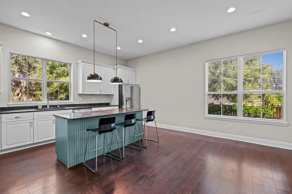 a kitchen with granite countertop a stove a sink a window and wooden floor