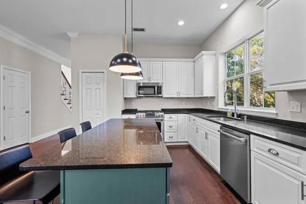 a kitchen with granite countertop kitchen island stainless steel appliances a sink a counter space and a window