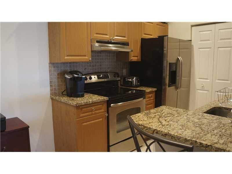 10312 Fox Trail Road South, Unit 1012 Royal Palm Beach, FL 33411 - Photo 2 of 6 a kitchen with a stove a refrigerator and furniture