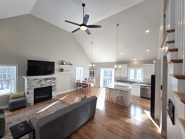 a living room with stainless steel appliances furniture a fireplace a flat screen tv and view kitchen