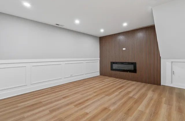 a view of empty room with wooden floor and fireplace