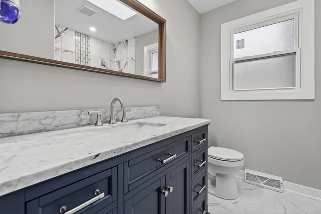 a bathroom with a granite countertop sink and a toilet