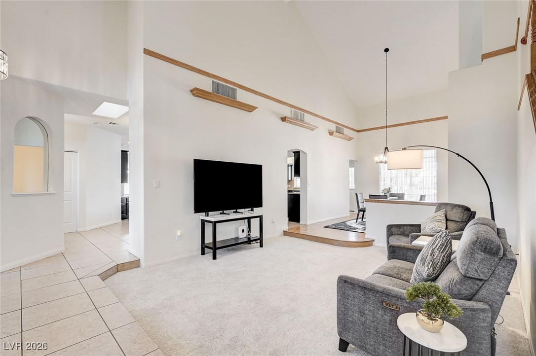 2955 El Camino Road Las Vegas, NV 89146 - Photo 36 of 99 Living area with high vaulted ceiling, light carpet, light tile patterned flooring, a chandelier, and arched walkways