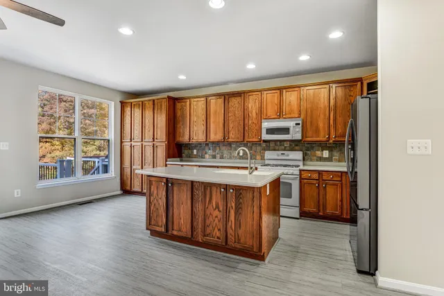 a kitchen with stainless steel appliances granite countertop a stove a sink dishwasher and a microwave oven with wooden floor