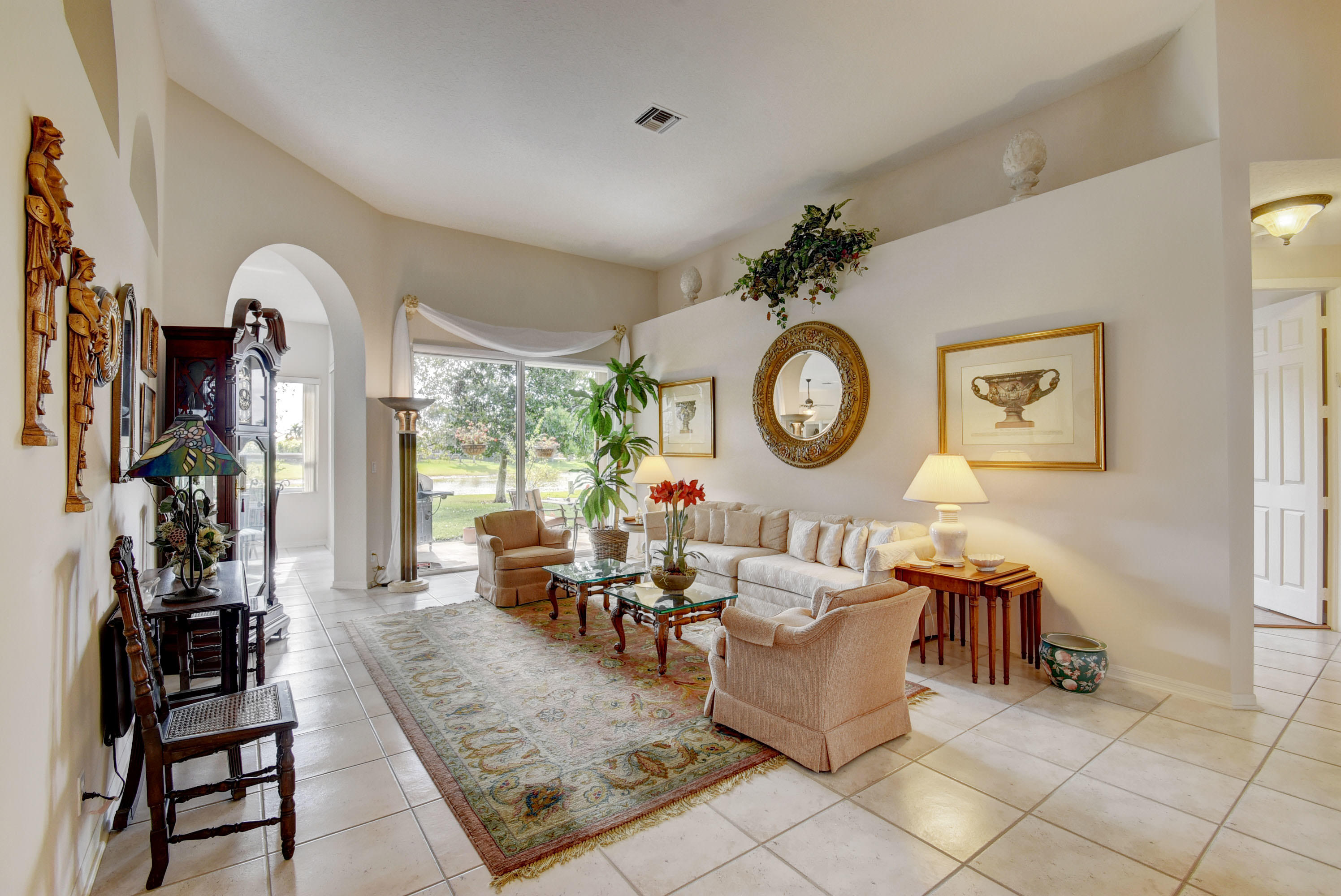21587 Halstead Drive Boca Raton, FL 33428 - Photo 6 of 53 a living room with couches a clock and a window with garden view