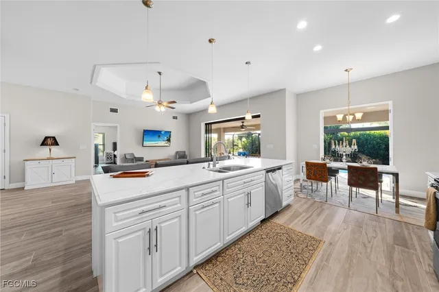 a kitchen with stainless steel appliances kitchen island granite countertop a refrigerator a stove a sink a dining table and chairs with wooden floor