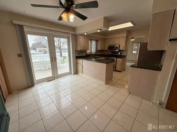 a living room with stainless steel appliances kitchen island granite countertop a refrigerator a stove top oven and a view of living room