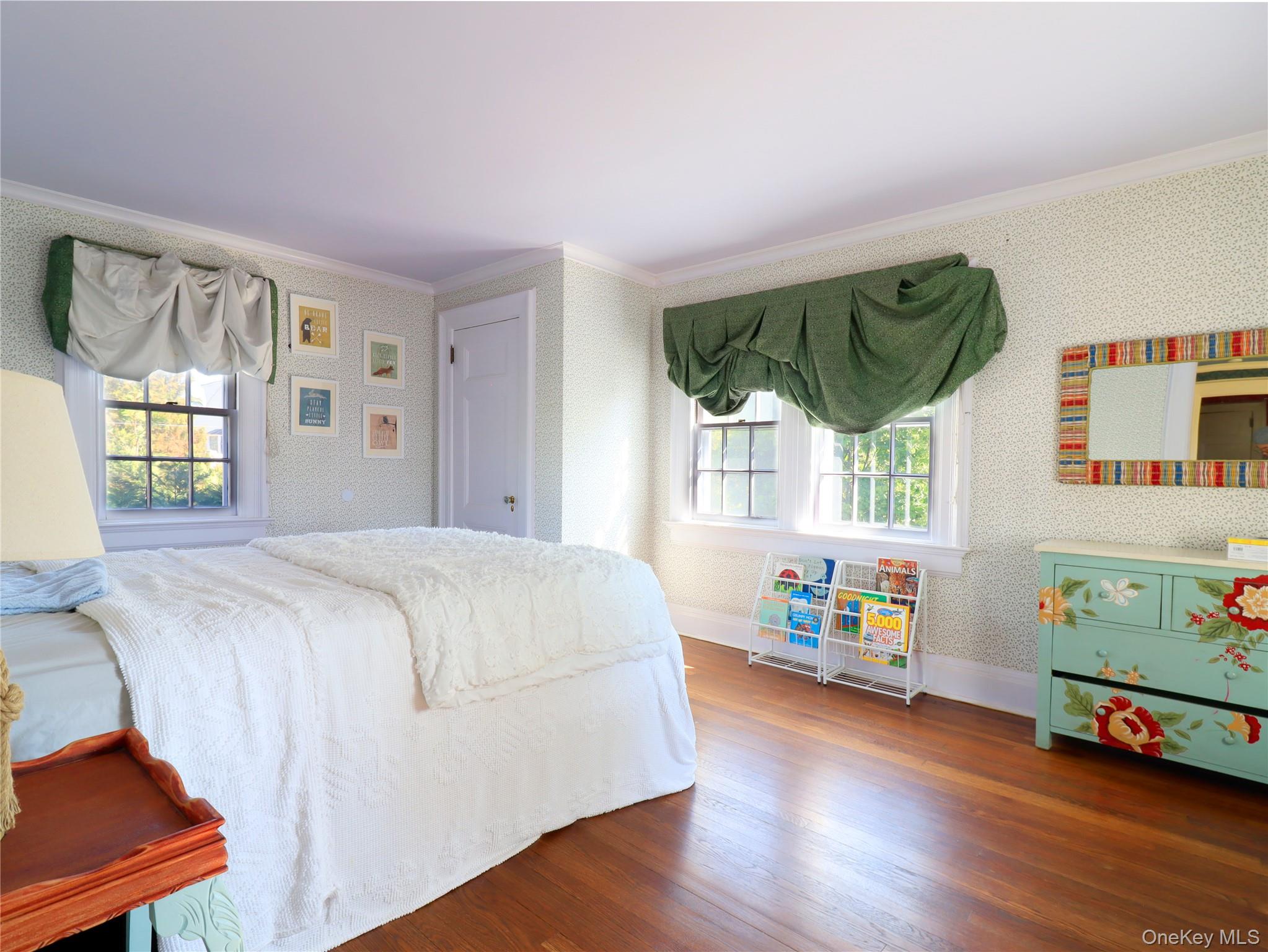 11-20 Shore Road Queens, NY 11363 - Photo 38 of 45 Bedroom featuring polished wood-finish flooring, light-toned patterned wallpaper, and two windows with green fabric valances