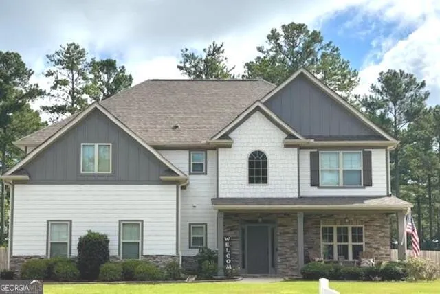 a view of a white house with large windows and a small yard