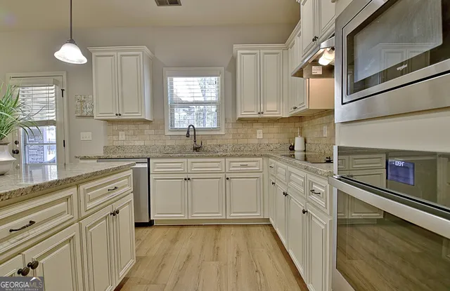 a kitchen with cabinets appliances and wooden floor