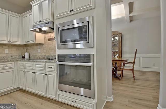 a kitchen with stainless steel appliances kitchen island granite countertop a table chairs sink and cabinets