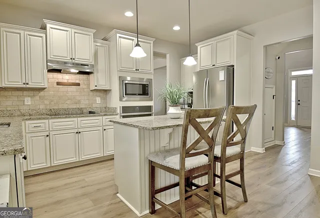 a kitchen with stainless steel appliances granite countertop a refrigerator a stove and a wooden floor