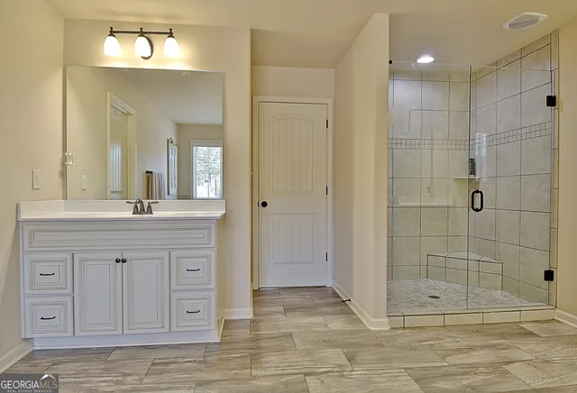 a spacious bathroom with a granite countertop sink a mirror a bathtub and a shower