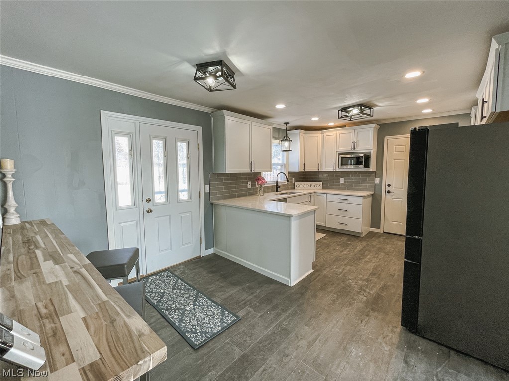 24709 Emery Road Warrensville Heights, OH 44128 - Photo 12 of 34 Kitchen with white cabinets, black refrigerator, tasteful backsplash, sink, and stainless steel microwave