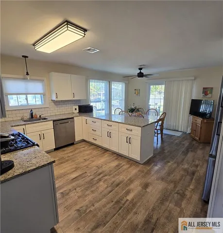 a large kitchen with a stove a sink dishwasher and a refrigerator with wooden floor