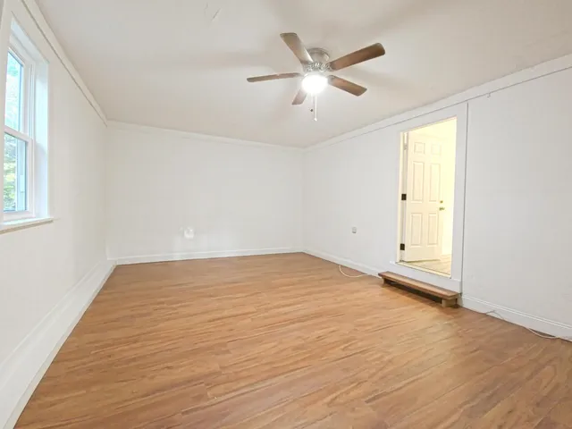 an empty room with wooden floor fan and windows