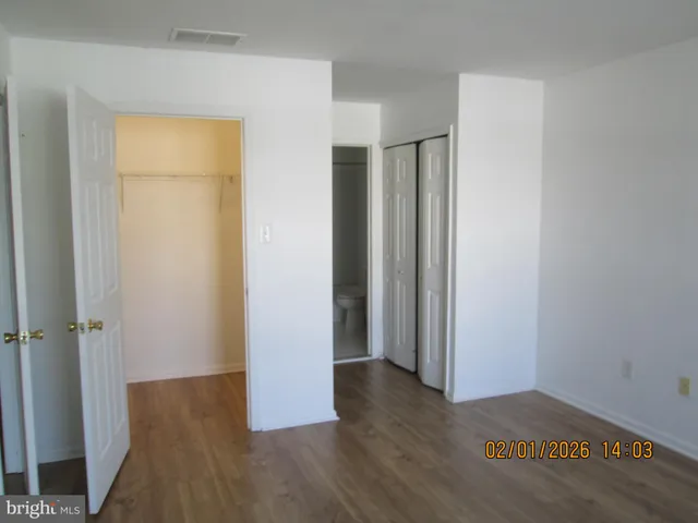 an empty room with wooden floor and a bathroom