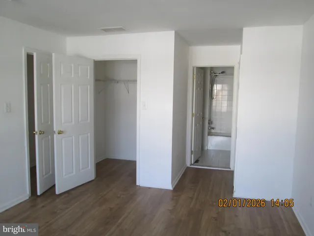 an empty room with wooden floor & closet area