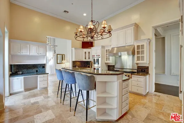a kitchen with stainless steel appliances granite countertop a sink a stove a refrigerator cabinets and chairs