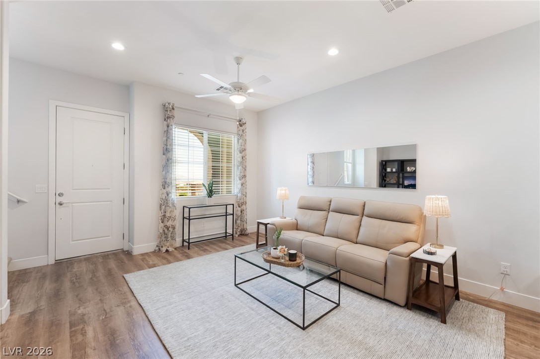 6432 Spring Jog Street Las Vegas, NV 89166 - Photo 9 of 61 Relax in this inviting living area, illuminated by recessed lighting and a ceiling fan, featuring durable hardwood flooring.