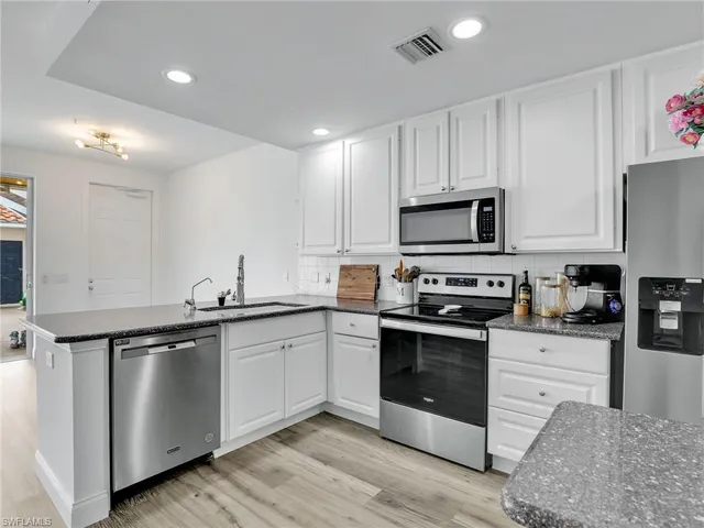 a kitchen with granite countertop a sink stainless steel appliances and white cabinets