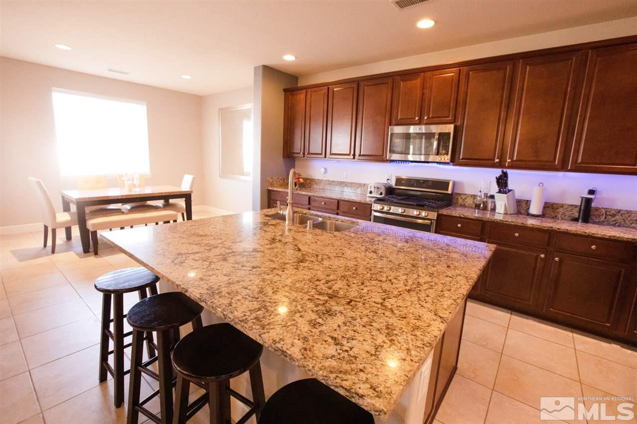 1885 Fledge Creek Drive Reno, NV 89521 - Photo 5 of 30 a kitchen with stainless steel appliances granite countertop a stove top oven a sink a refrigerator white cabinets and wooden furniture