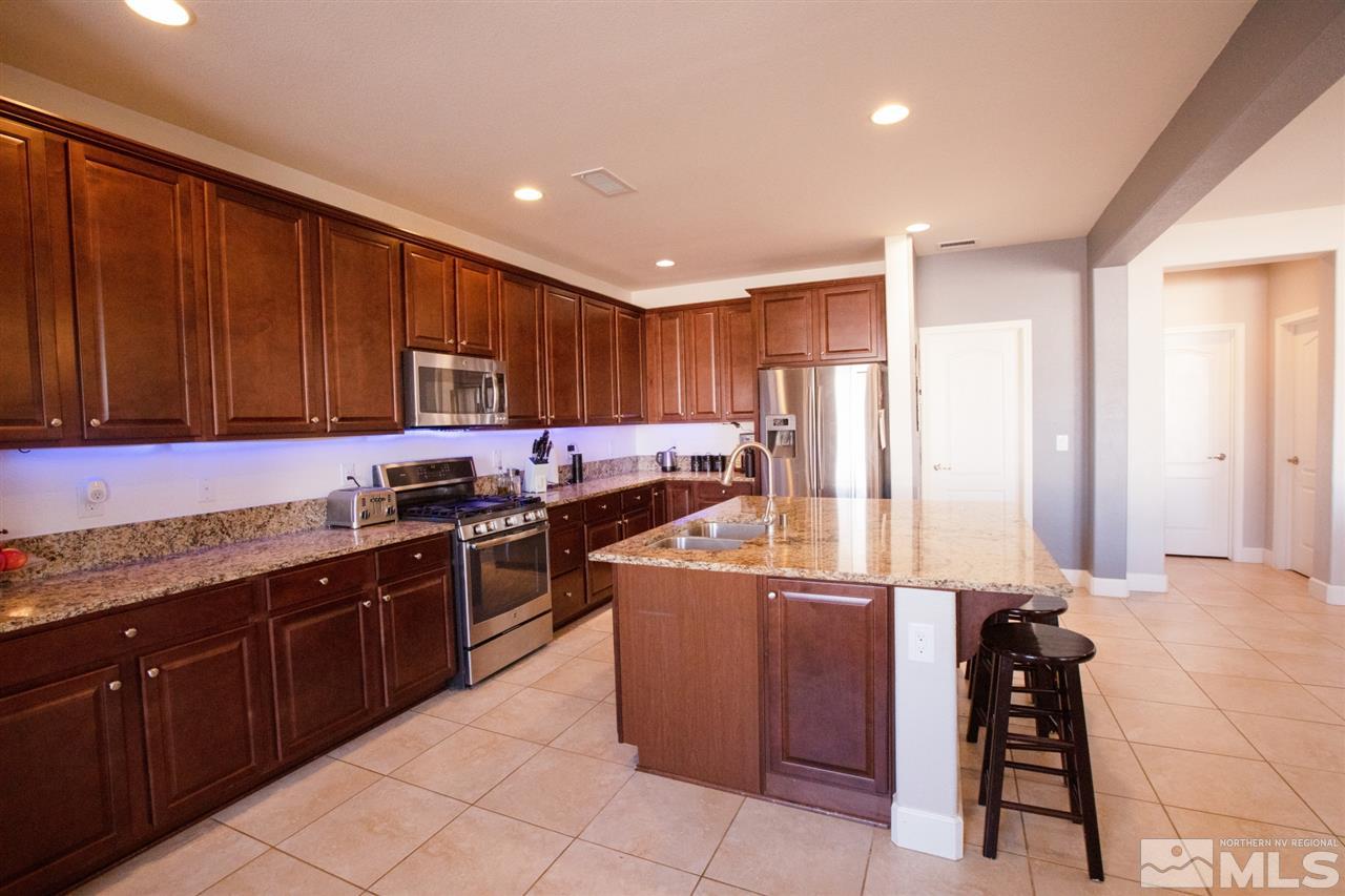 1885 Fledge Creek Drive Reno, NV 89521 - Photo 7 of 30 a kitchen with stainless steel appliances granite countertop wooden cabinets a stove top oven and granite counter tops