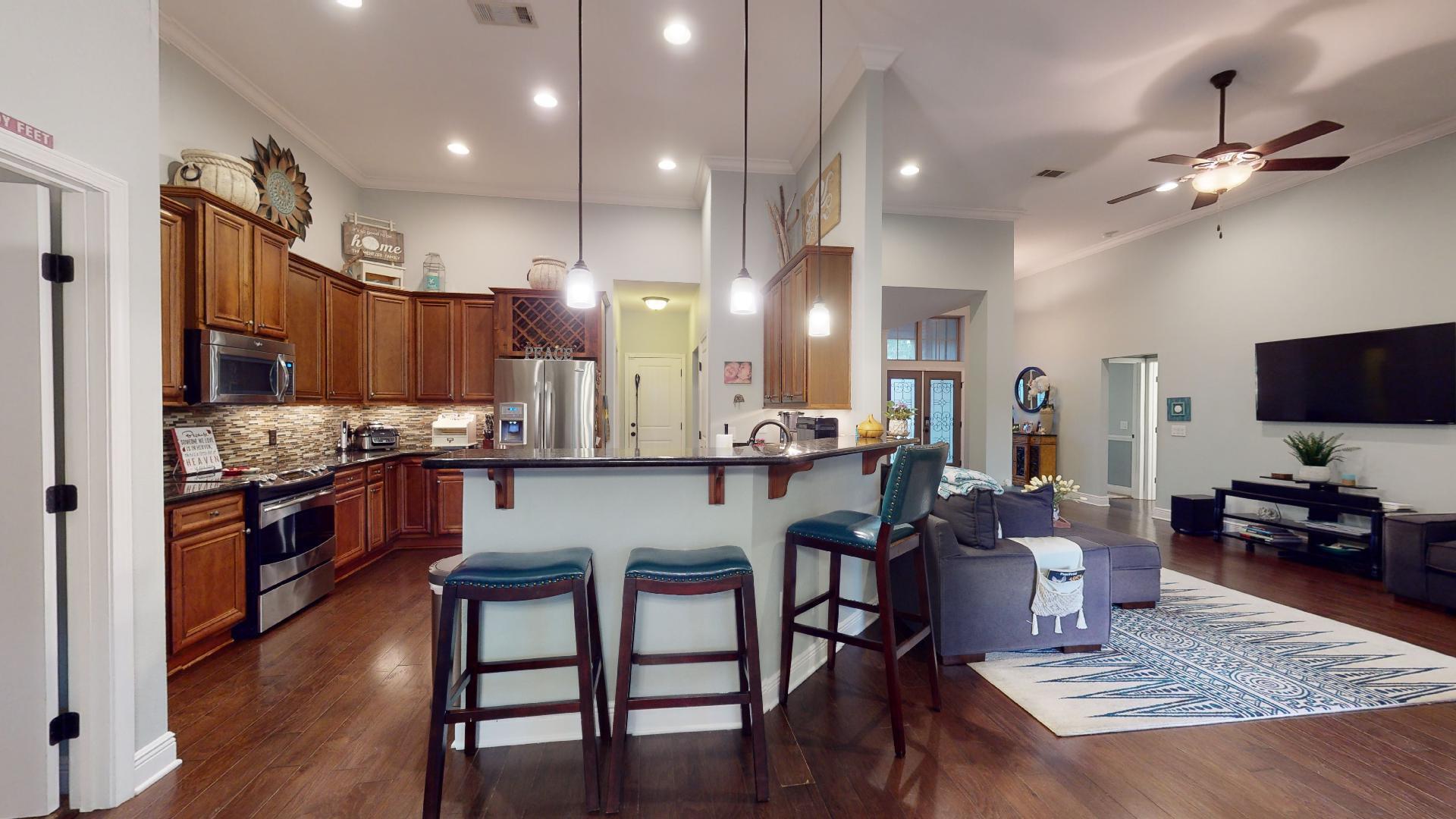 1959 Commodore Drive Navarre, FL 32566 - Photo 17 of 56 a kitchen with stainless steel appliances granite countertop a stove a refrigerator a kitchen island a dining table and chairs with wooden floor
