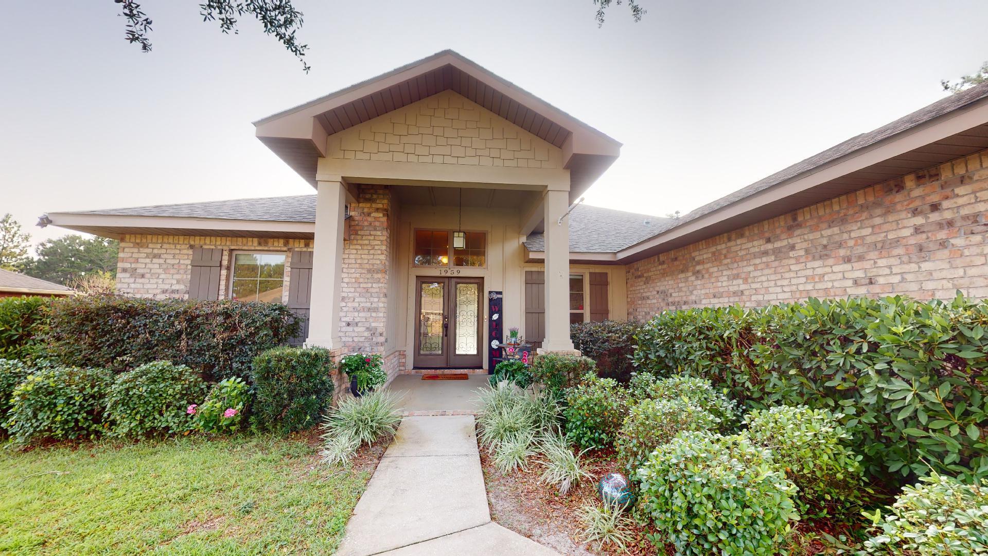 1959 Commodore Drive Navarre, FL 32566 - Photo 2 of 56 a front view of a house with garden