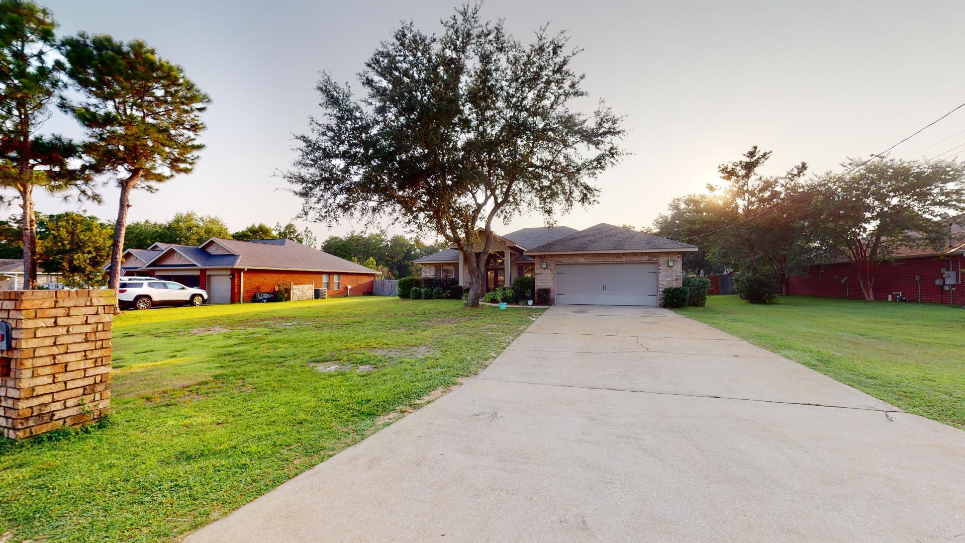 1959 Commodore Drive Navarre, FL 32566 - Photo 6 of 56 a front view of a house with a garden and trees