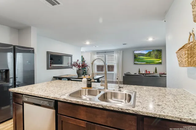 a kitchen with kitchen island granite countertop a sink and a refrigerator