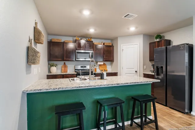 a kitchen with kitchen island granite countertop a sink cabinets and stainless steel appliances