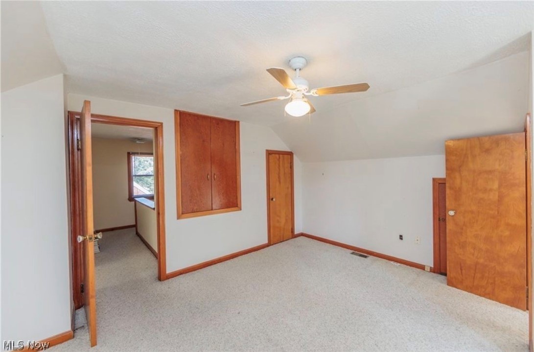 4521 Emerson Road South Euclid, OH 44121 - Photo 29 of 47 Carpeted room featuring a ceiling fan with light fixture, multiple wood-paneled doors, wood trim, and a built-in wood cabinet