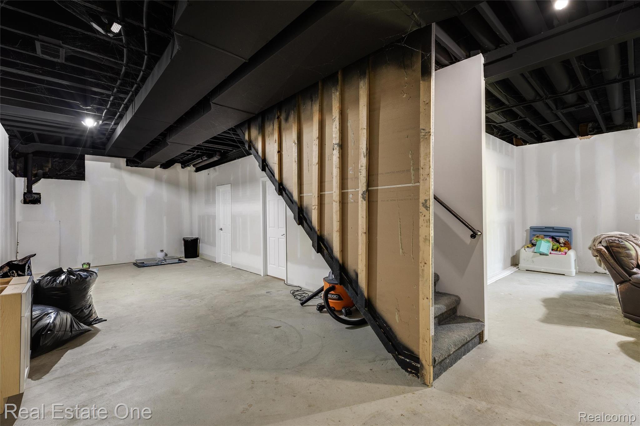 2983 28 Mile Road Washington, MI 48094 - Photo 32 of 54 Unfinished basement with a concrete floor, painted black exposed ceiling joists and ductwork, recessed lighting, and partial drywall installation