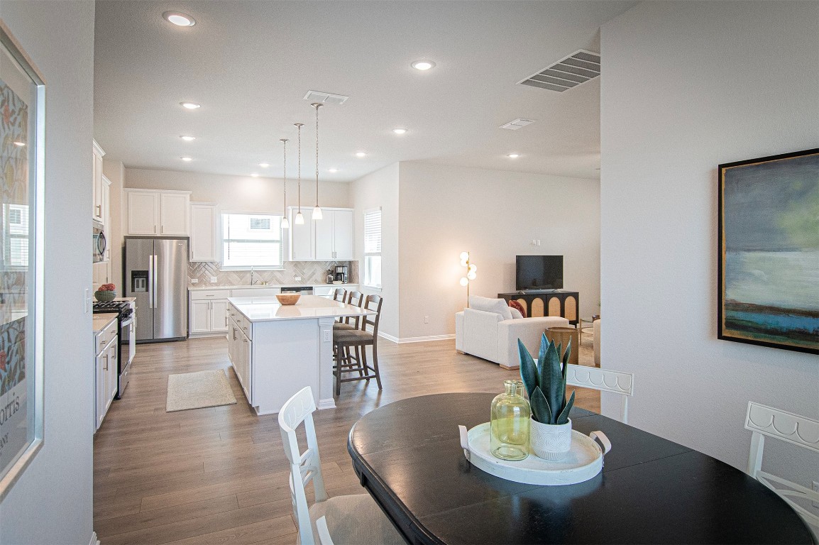 249 Treadwell Lane Kyle, TX 78640 - Photo 12 of 32 a kitchen with a dining table wooden floor and kitchen view