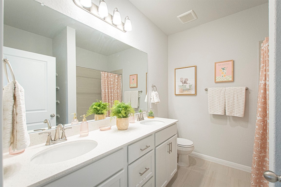 249 Treadwell Lane Kyle, TX 78640 - Photo 27 of 32 a bathroom with a double vanity sink toilet and a mirror