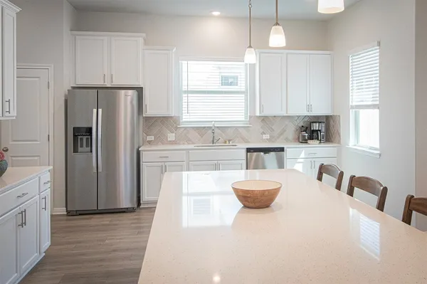 a kitchen with a refrigerator a sink dishwasher a stove and white cabinets with wooden floor