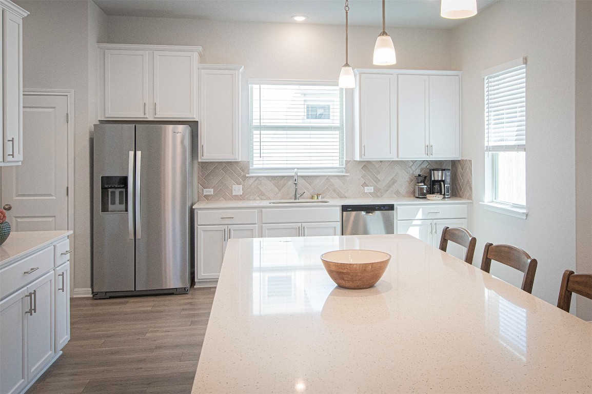249 Treadwell Lane Kyle, TX 78640 - Photo 8 of 32 a kitchen with a refrigerator a sink dishwasher a stove and white cabinets with wooden floor