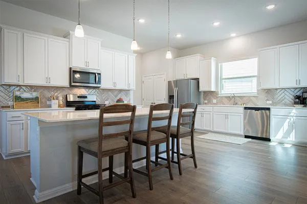 a kitchen with a table chairs refrigerator and microwave