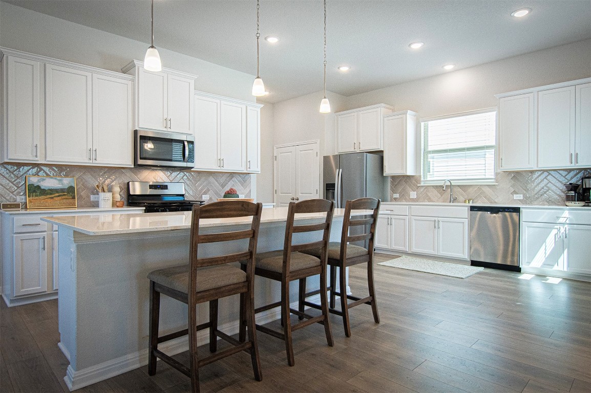 249 Treadwell Lane Kyle, TX 78640 - Photo 9 of 32 a kitchen with a table chairs refrigerator and microwave