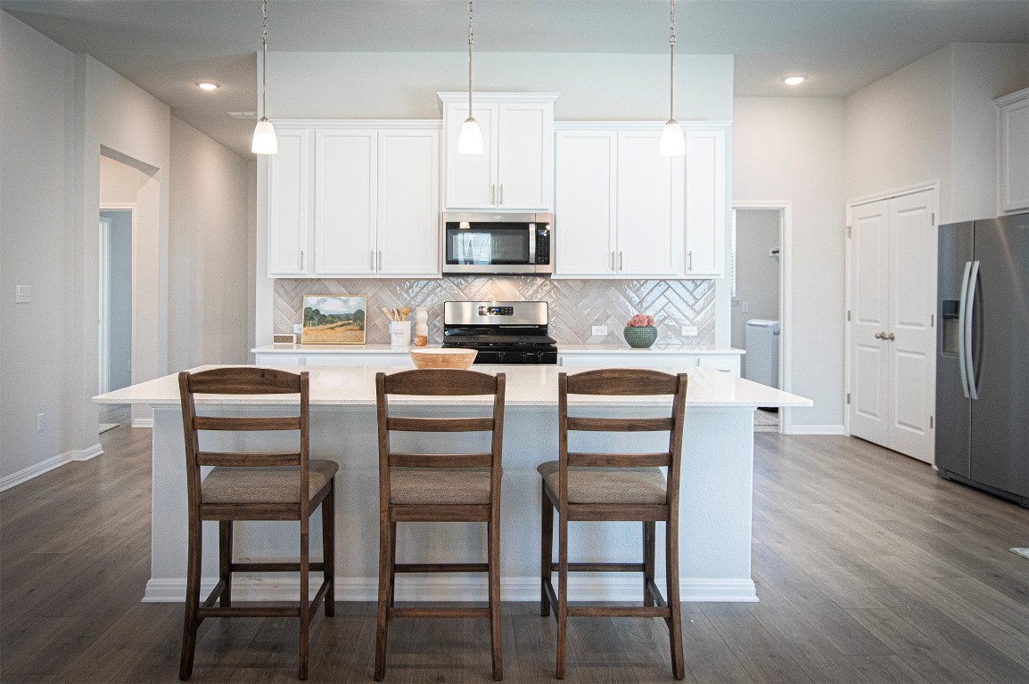 249 Treadwell Lane Kyle, TX 78640 - Photo 10 of 32 a kitchen with stainless steel appliances granite countertop a dining table chairs refrigerator and microwave