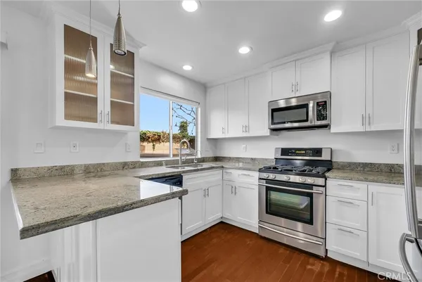 a kitchen with stainless steel appliances granite countertop a stove a sink and a microwave