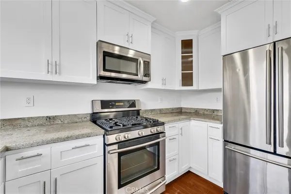 a kitchen with stainless steel appliances granite countertop white cabinets granite counter tops and a stove top oven