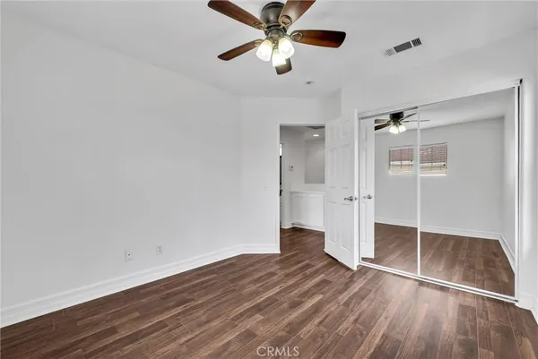 a view of empty room with wooden floor and fan