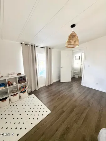 a spacious bedroom with a bed and wooden floor