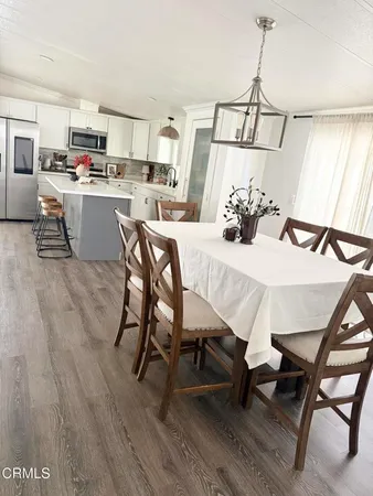 a kitchen with a sink a microwave a refrigerator and chairs