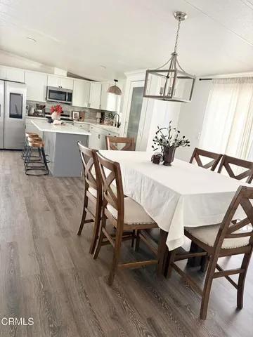 a kitchen with a sink a microwave a refrigerator and chairs